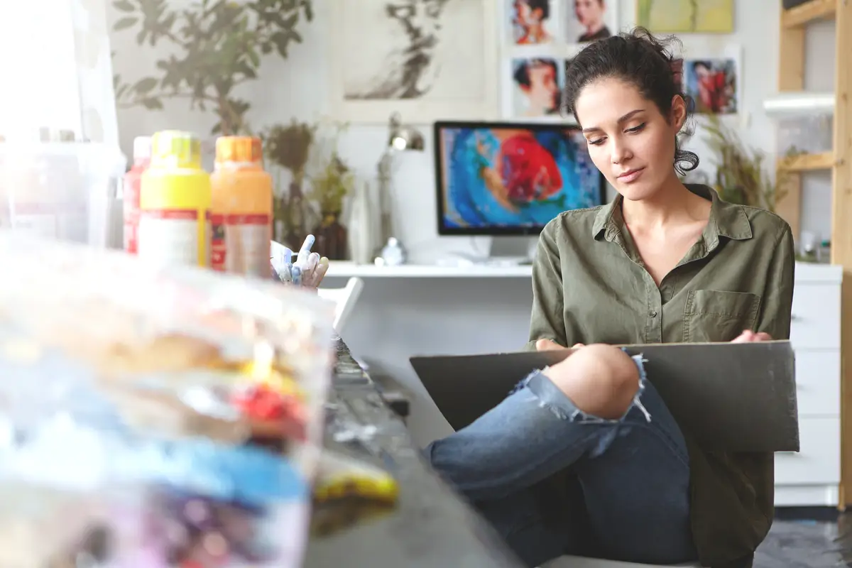 Attractive brunette young European woman artist expressing her ideas through painting, feeling happy about her occupation, enjoying process of creating something new. Art, craft and creativity