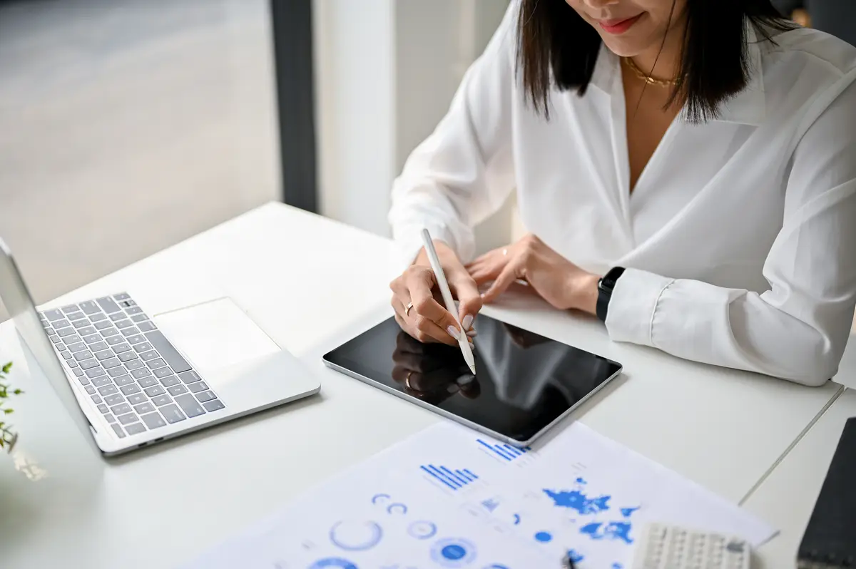 Cropped image of an Asian businesswoman using her digital tablet working on financial tasks