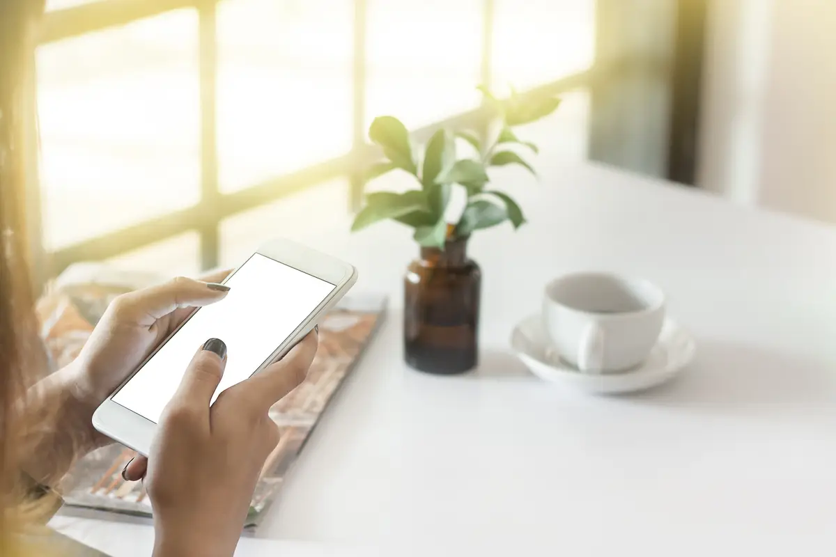 Cropped hands of woman using phone at table