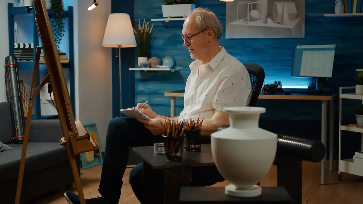 Old creative artist taking notes on paper to draw vase model sketch, using textbook for inspiration and creativity. Drawing artistic design with authentic tools, create masterpiece.