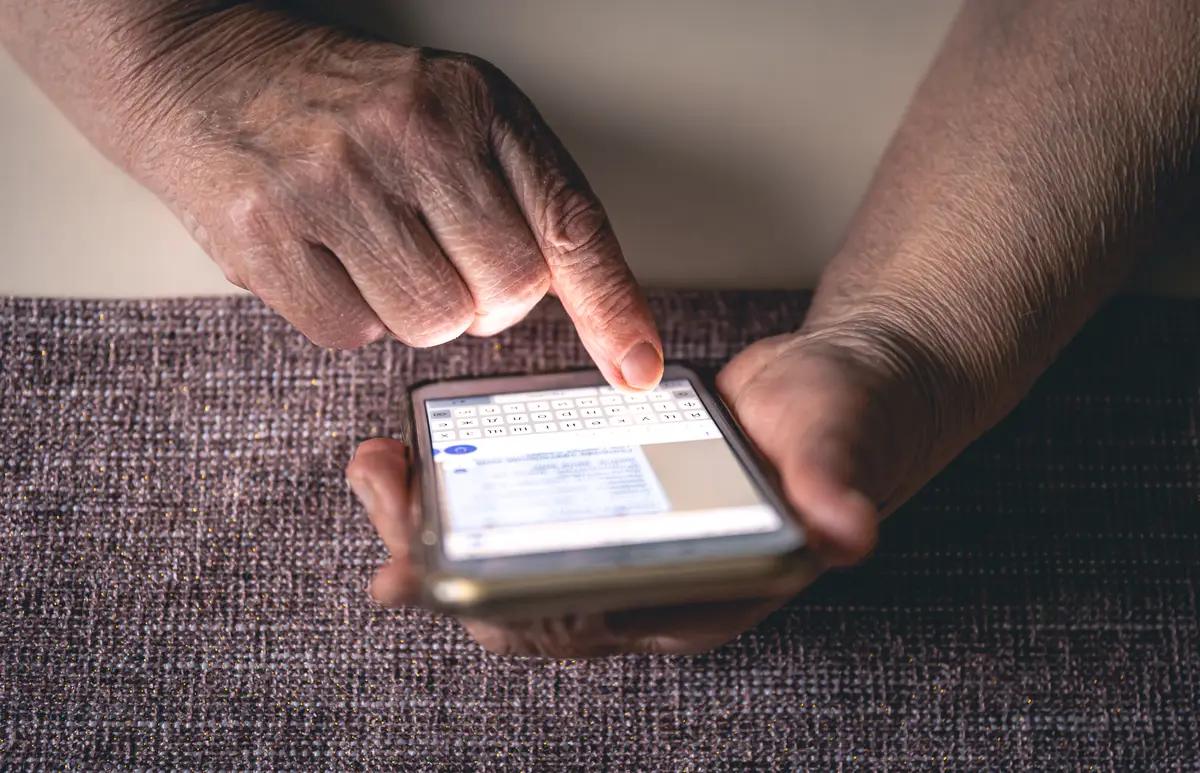 Hands of an elderly woman holding a mobile phone