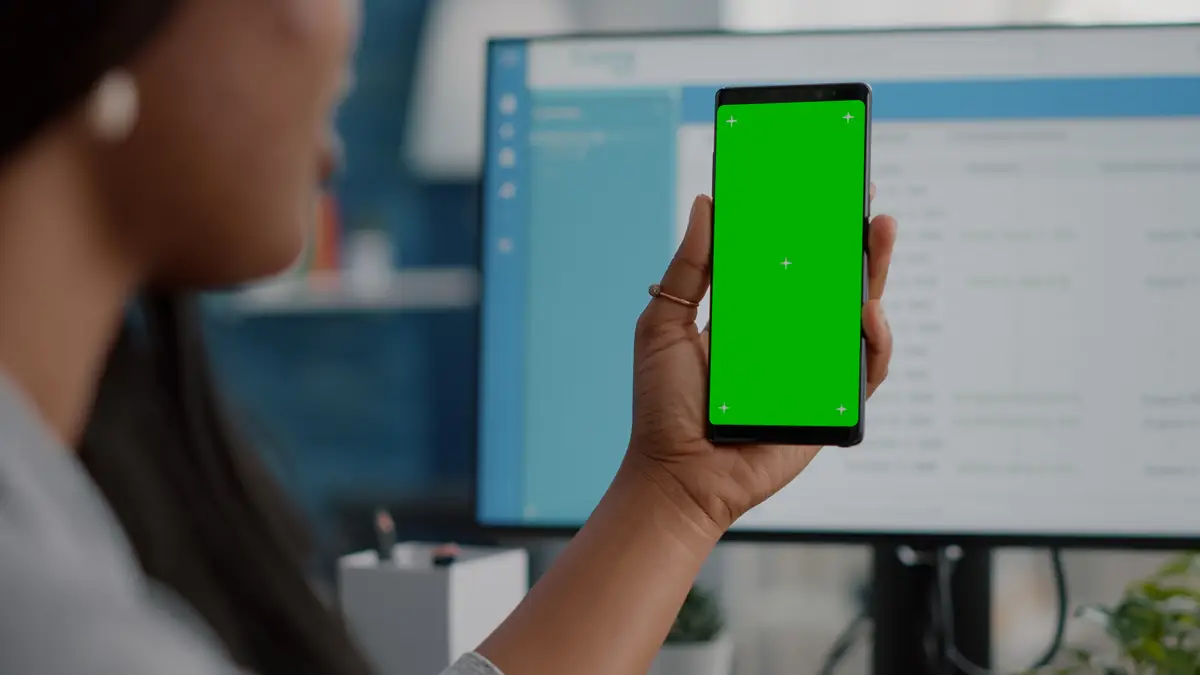 Closeup of african woman holding mock up green screen chroma key phone with isolated display
