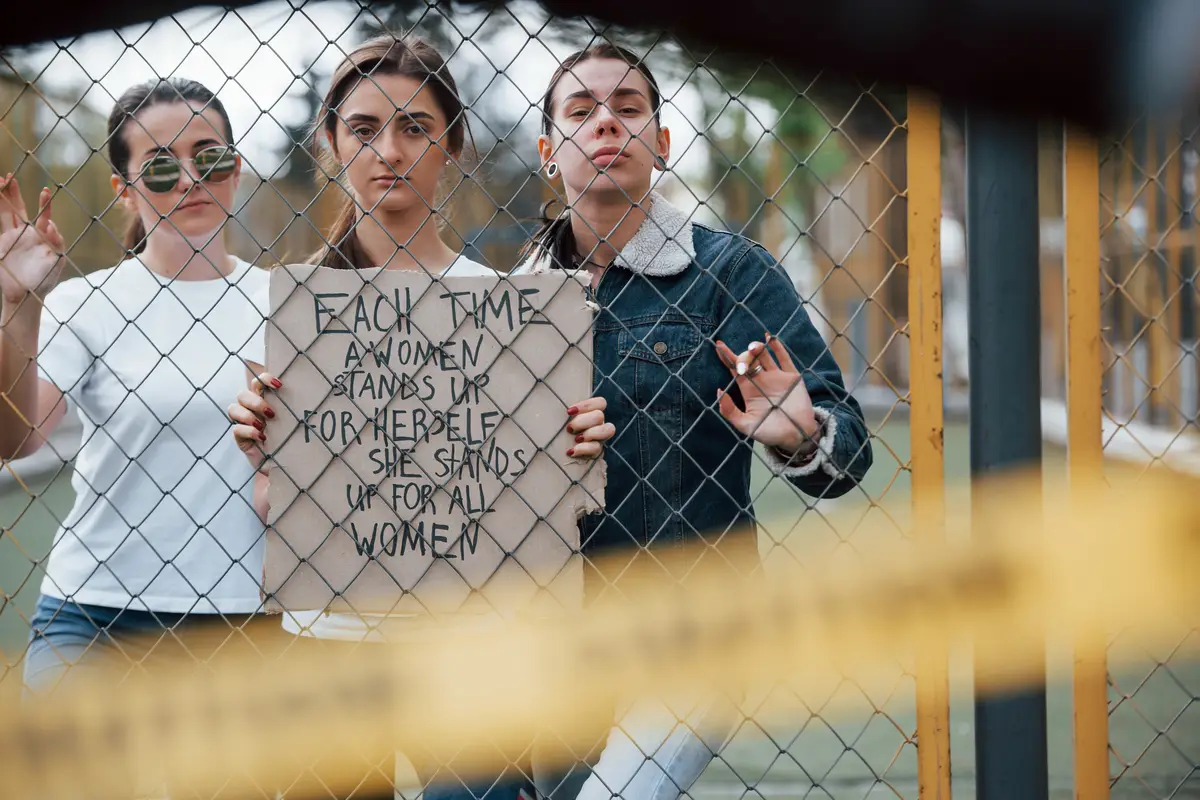 Through the fence. Group of feminist women have protest for their rights outdoors