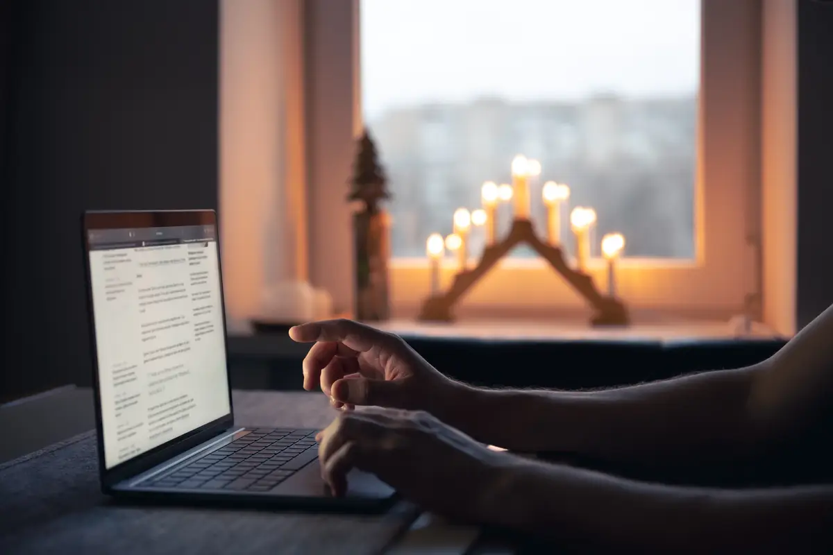 A man reads the news while sitting in front of a laptop screen at night