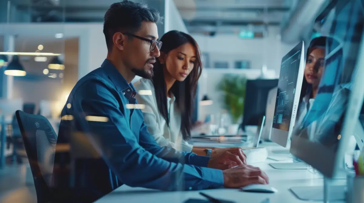 An office scene with a diverse business team including a male and a female colleague working together and using technology to strategize