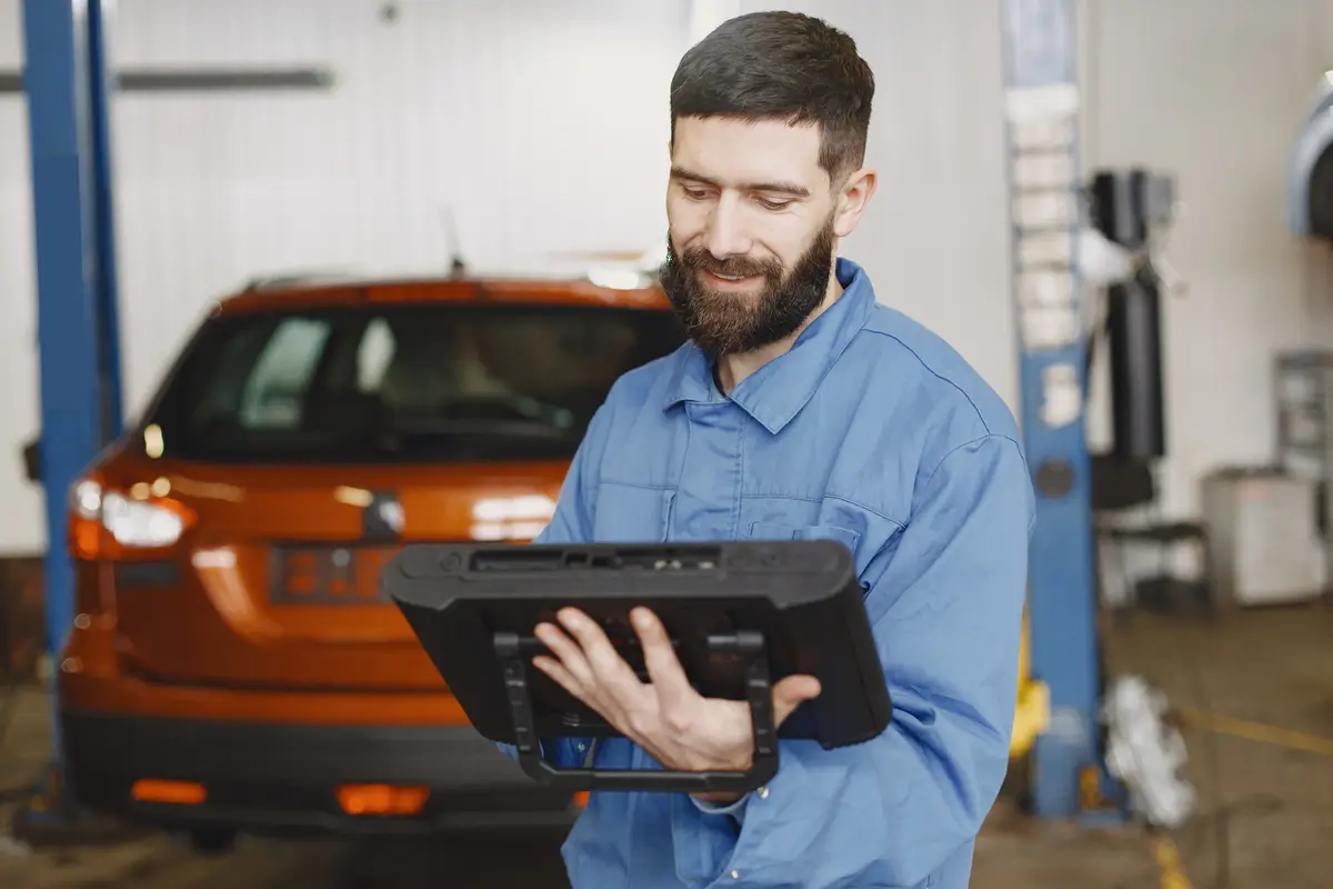 Car mechanic with a tablet near car in work clothes