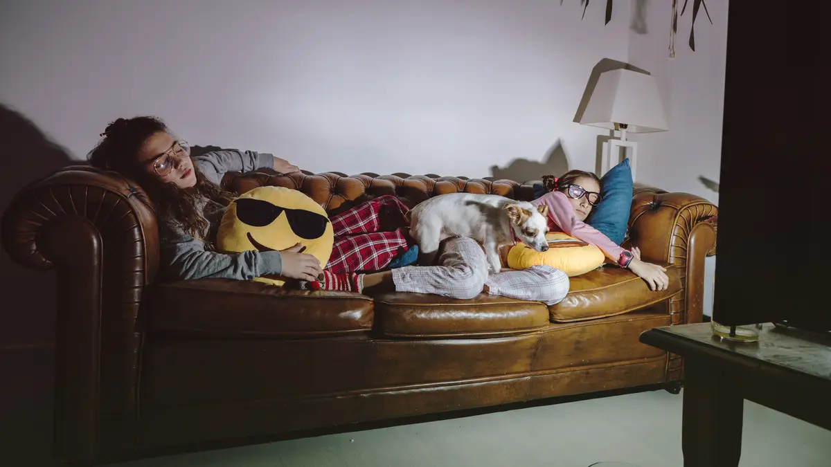 Sleeping girls on sofa with TV turned