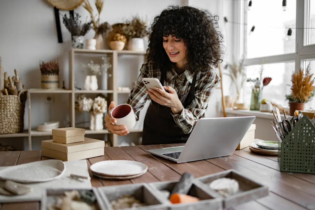 Girl store employee with ceramic tableware shoots photos on smartphone