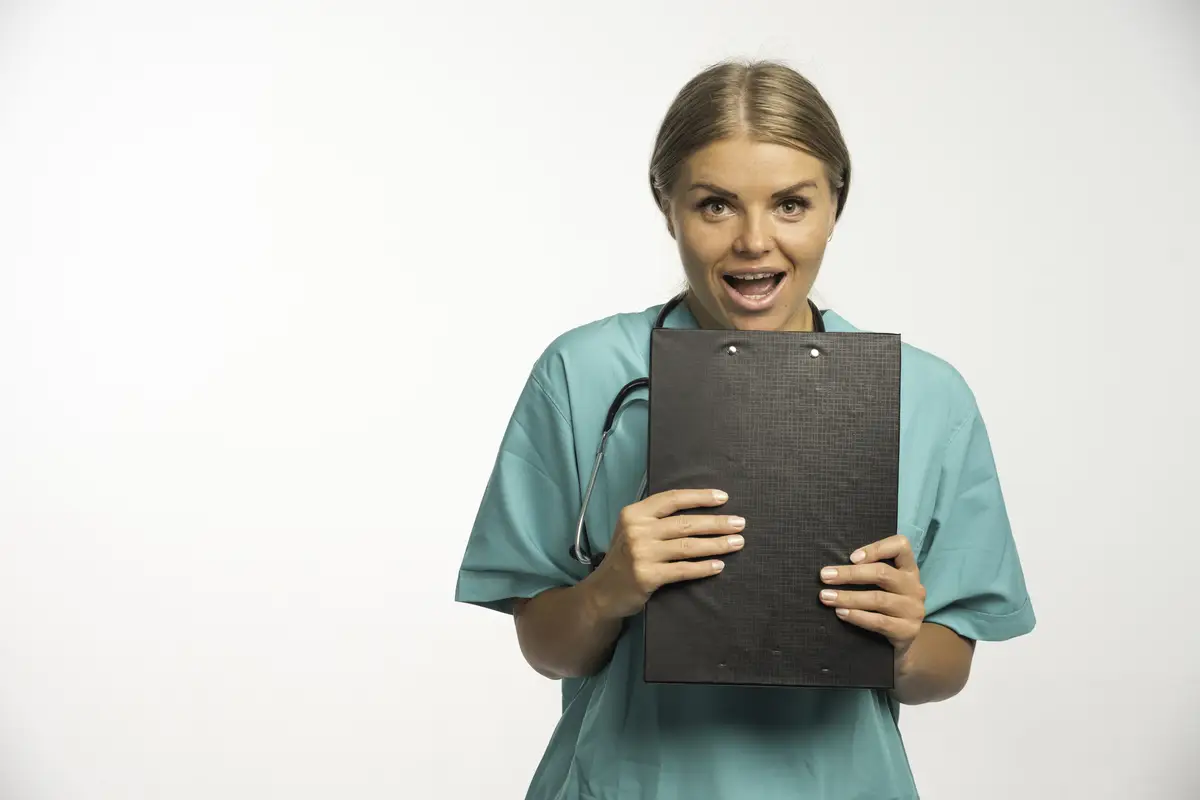 Blonde female doctor in blue uniform holding a receipt book and looks excited.