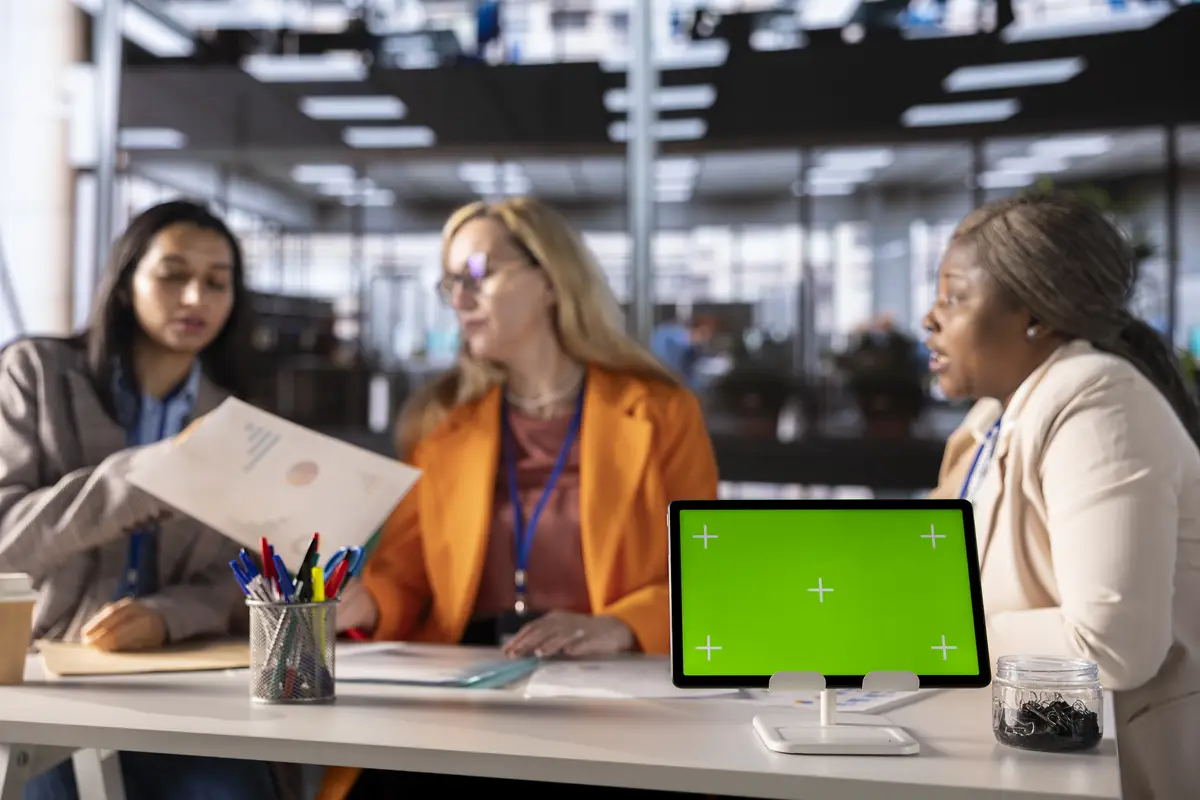 Multiethnic businesswomen working next to isolated green screen