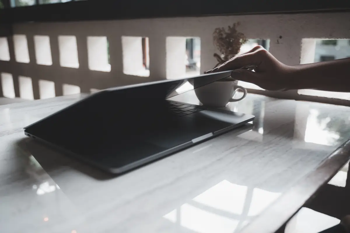 Hands close and open a laptop on table