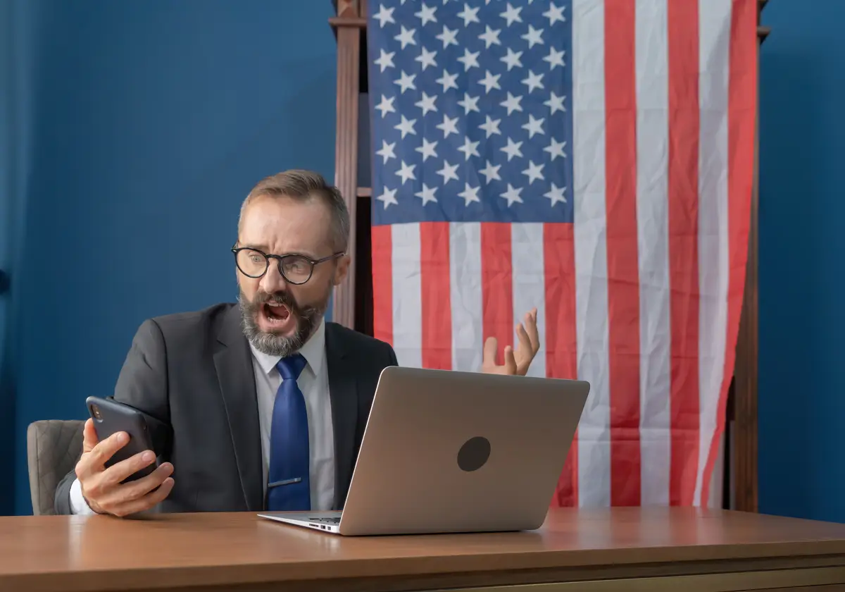 Man using mobile phone while sitting on laptop