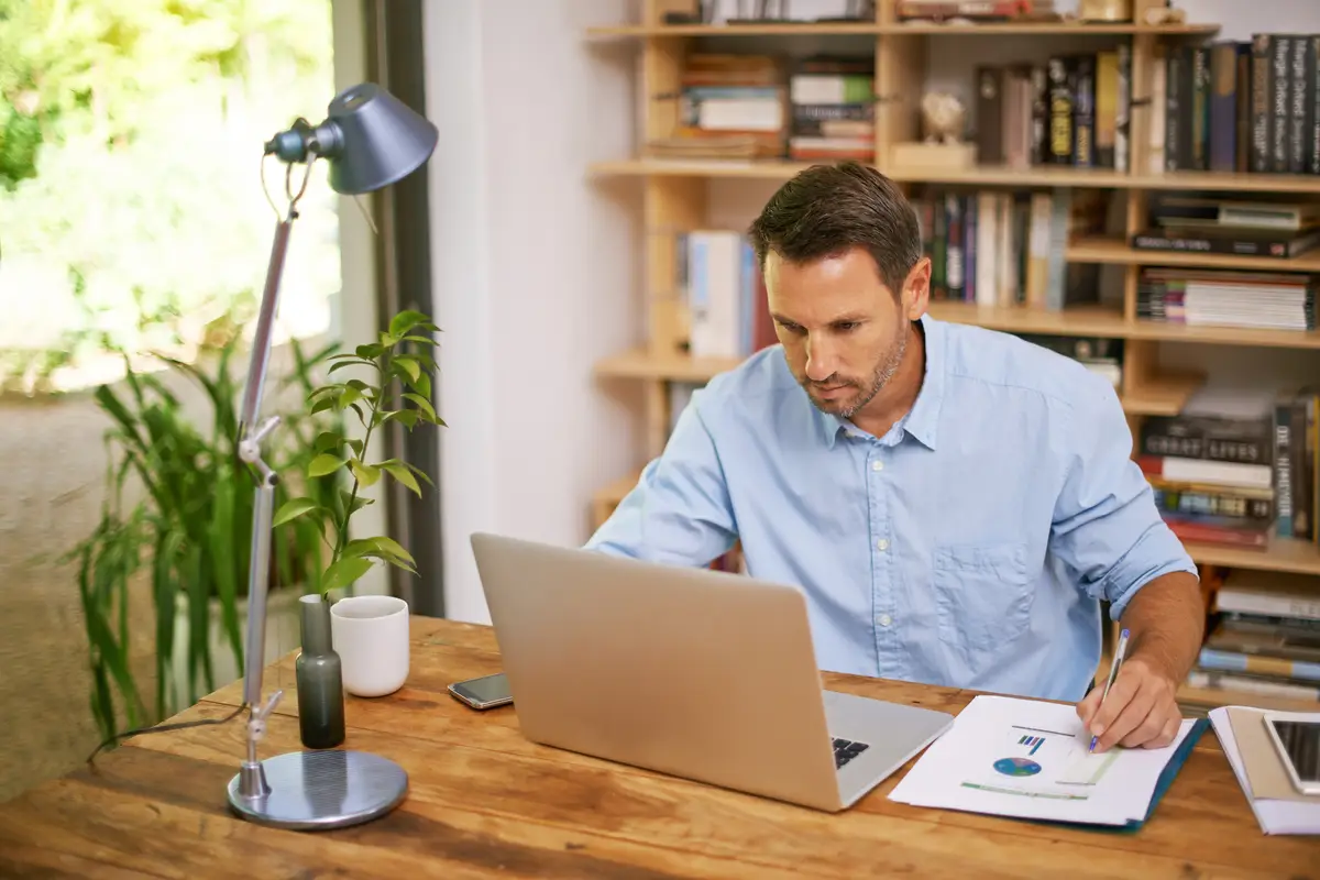 Paperwork planning and man in home office with laptop business stats and professional with online research Remote work data analysis and consultant at computer documents and financial report