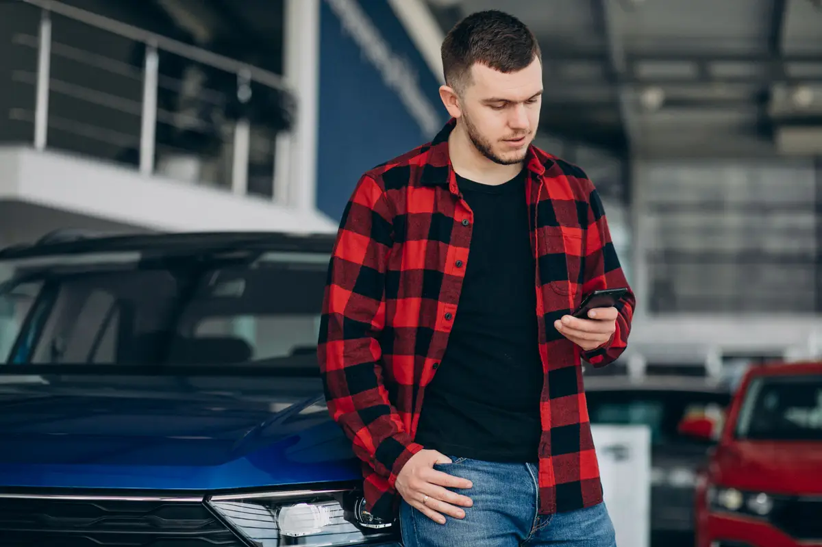Young man choosing a car in a car showroom