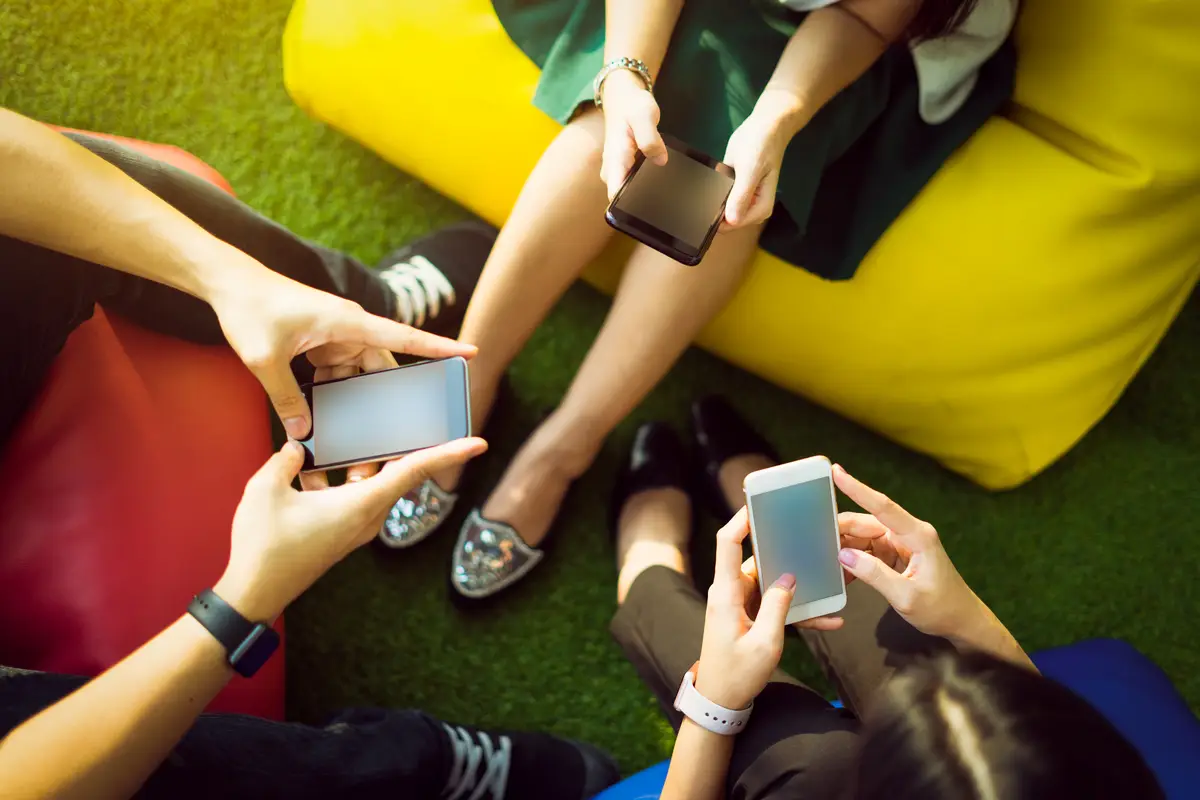 Group of three young people using smartphones together, modern lifestyle or communication technology gadget concept.