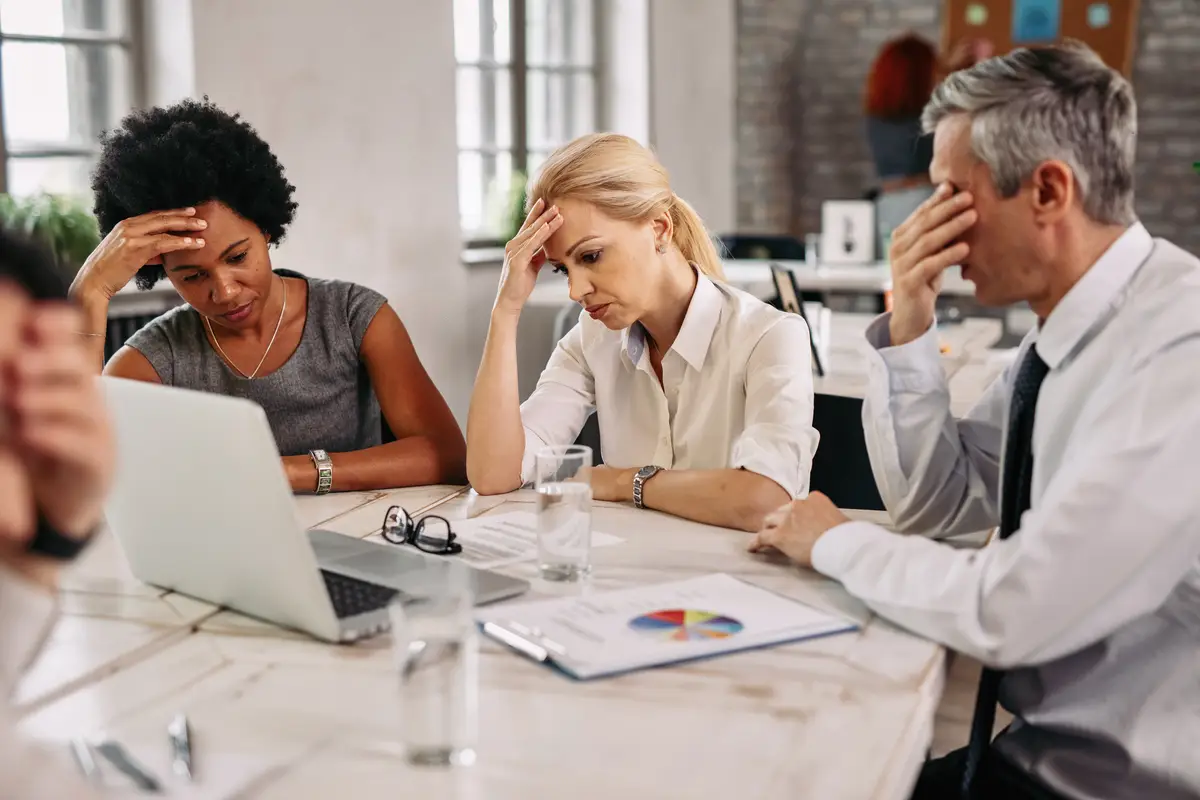 Group of business colleagues having a headache while working on laptop and trying to solve the problems during a meeting
