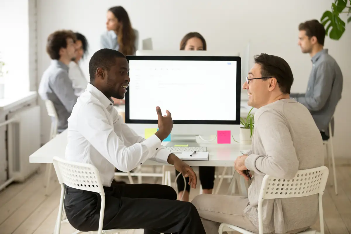 Friendly smiling diverse male colleagues having pleasant conversation at work