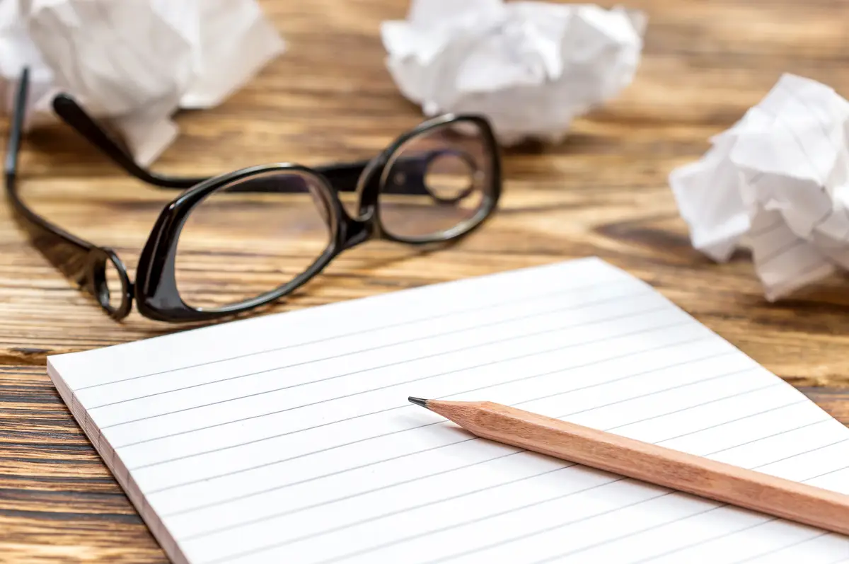 Notepad with crumpled up sheets and glasses on the table