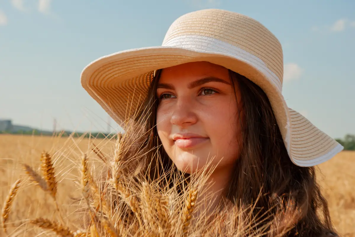 Portrait of woman in straw hat amidst wheat field on sunny day Harvesting concept