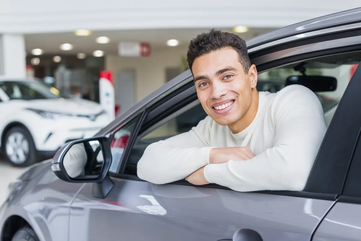 Happy man in car dealership