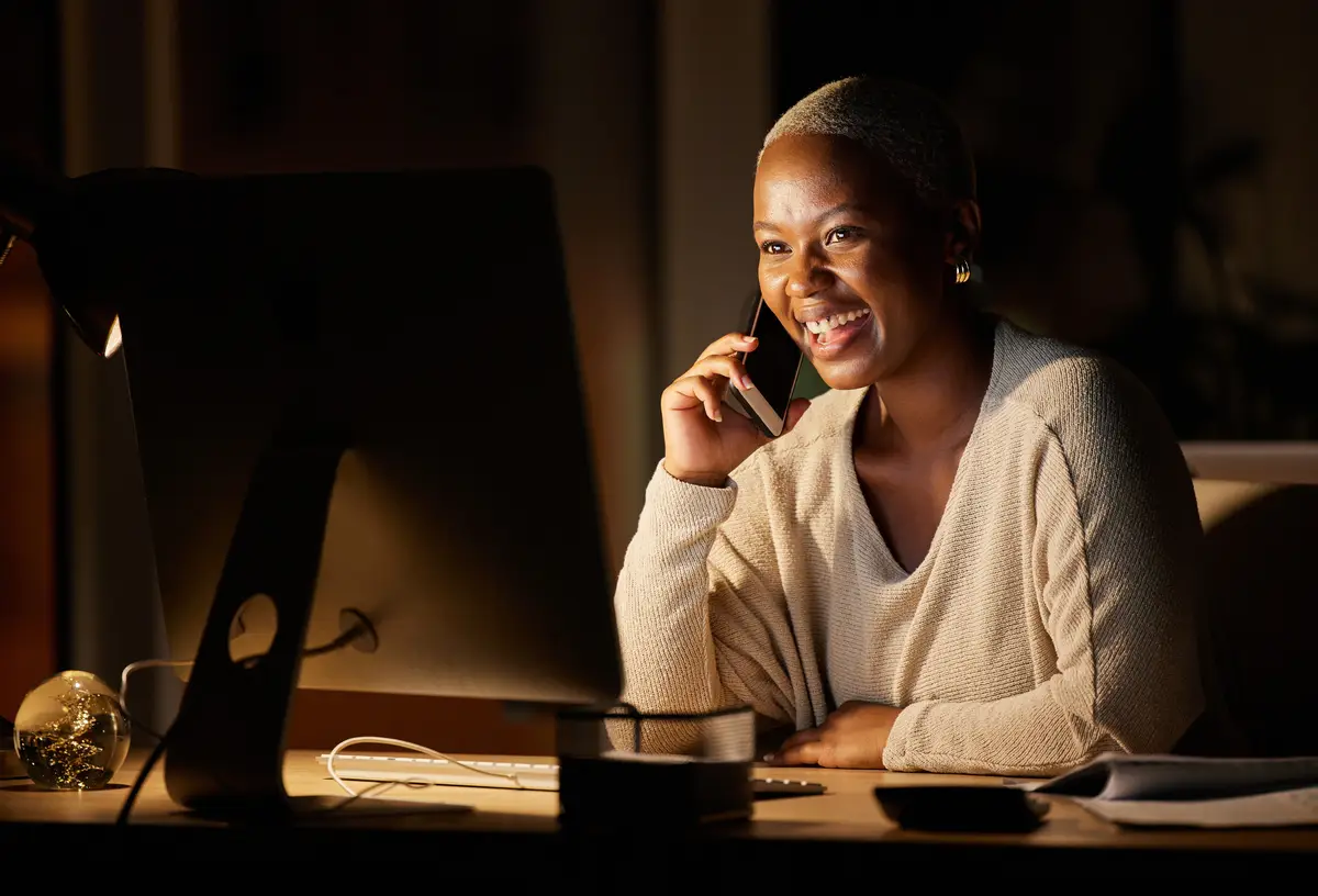 Phone call business and black woman in office at night for contact online discussion and networking Professional happy and person on smartphone and computer for internet website or communication