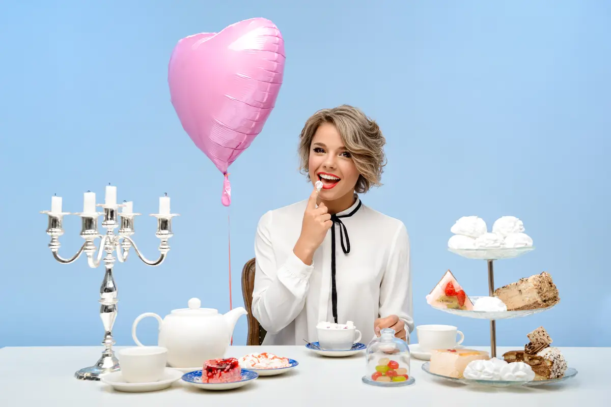 Portrait of young beautiful woman with sweets over blue wall