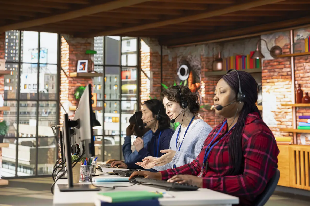 Team of multiethnic call center workers typing on PC keyboard assisting clients