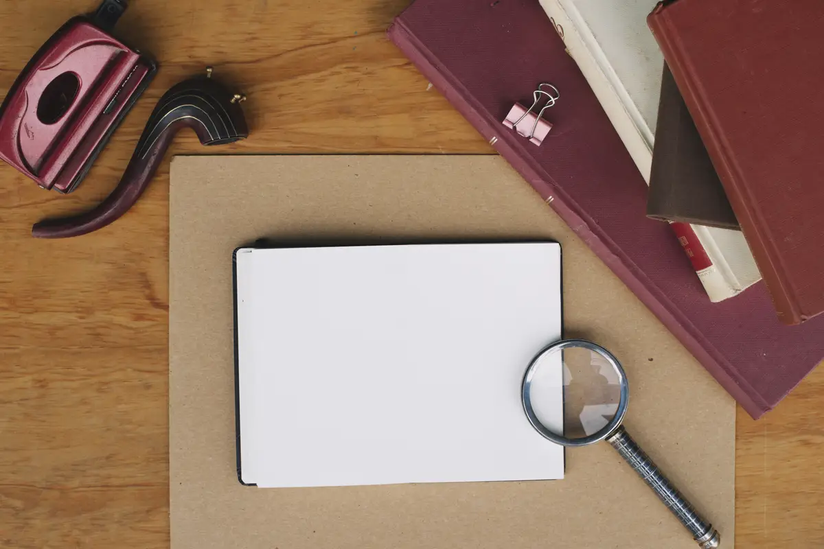 Stack of books and magnifying glass near notebook