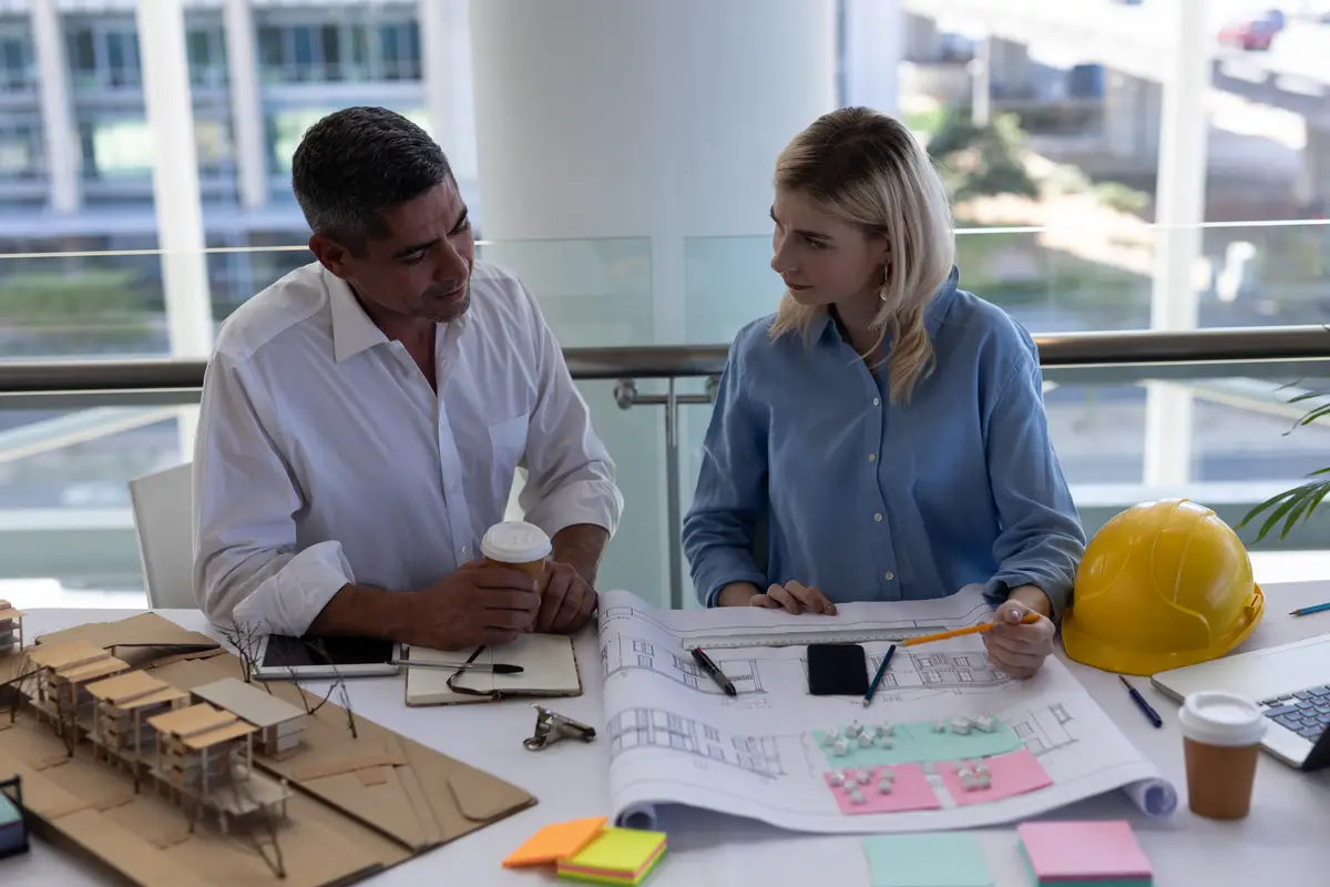 Caucasians architects discussing over blueprint at desk in office