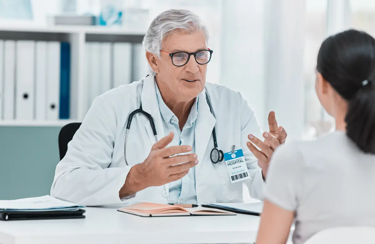Mature doctor patient and consultation in clinic for healthcare checkup results and advice Medical professional man and conversation for help exam and explain treatment in hospital appointment