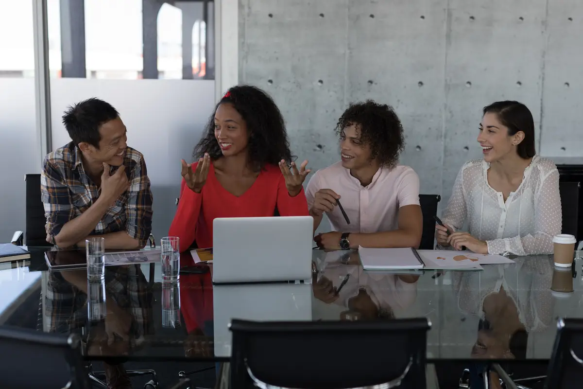 Happy executives talking with each other at table in office