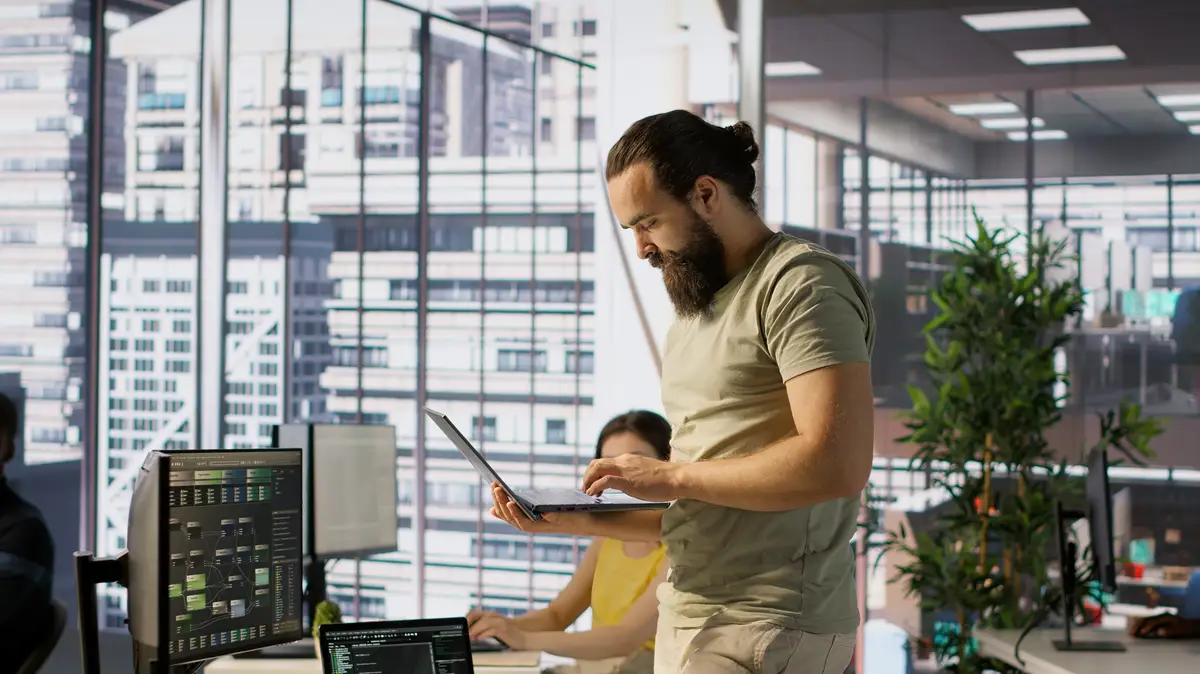 Man monitoring company systems using notebook while standing in office