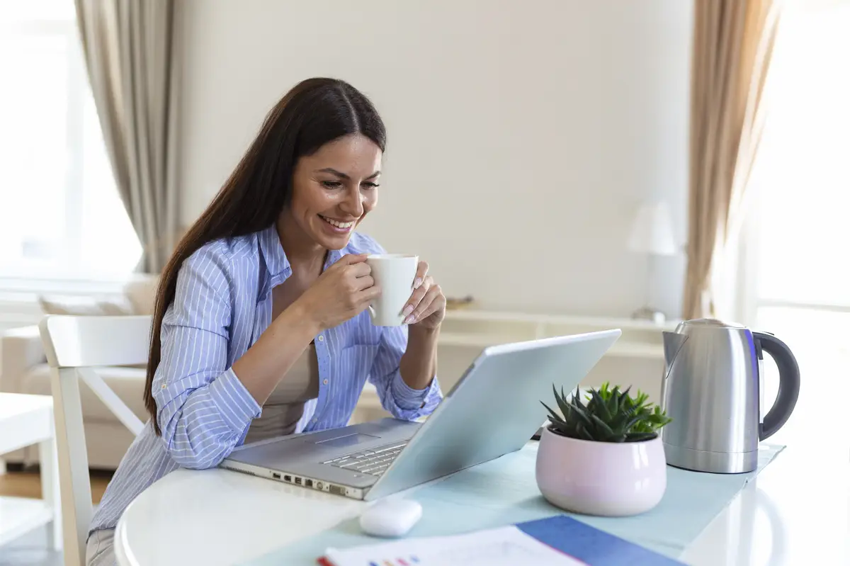 Self employed woman working with her laptop at home with a cup of coffee