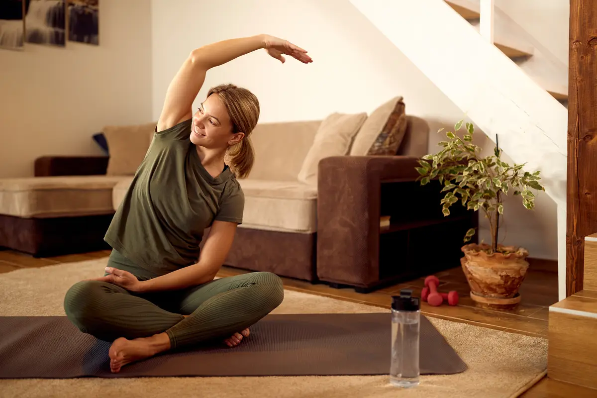 Happy athletic woman doing stretching exercises during home workout