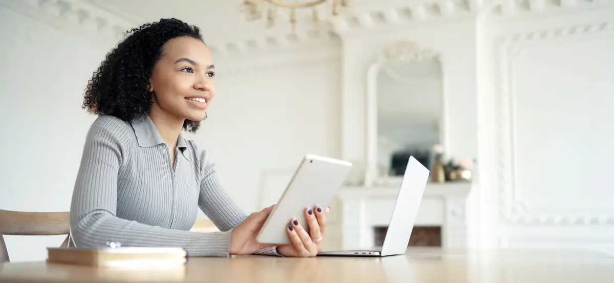 Focused businesswoman multitasking with tablet and laptop in a classic home office epitomizing