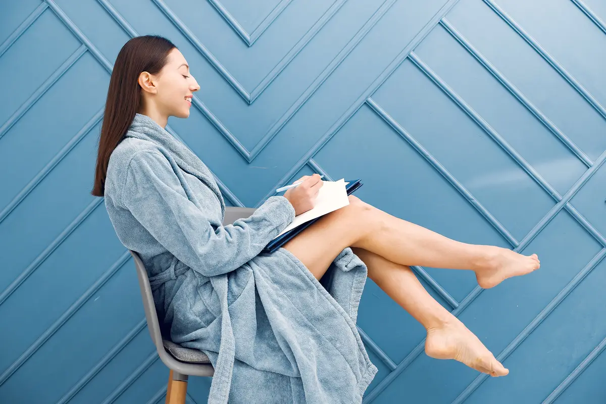 Beautiful girl standing in a studio in a blue bathrobe