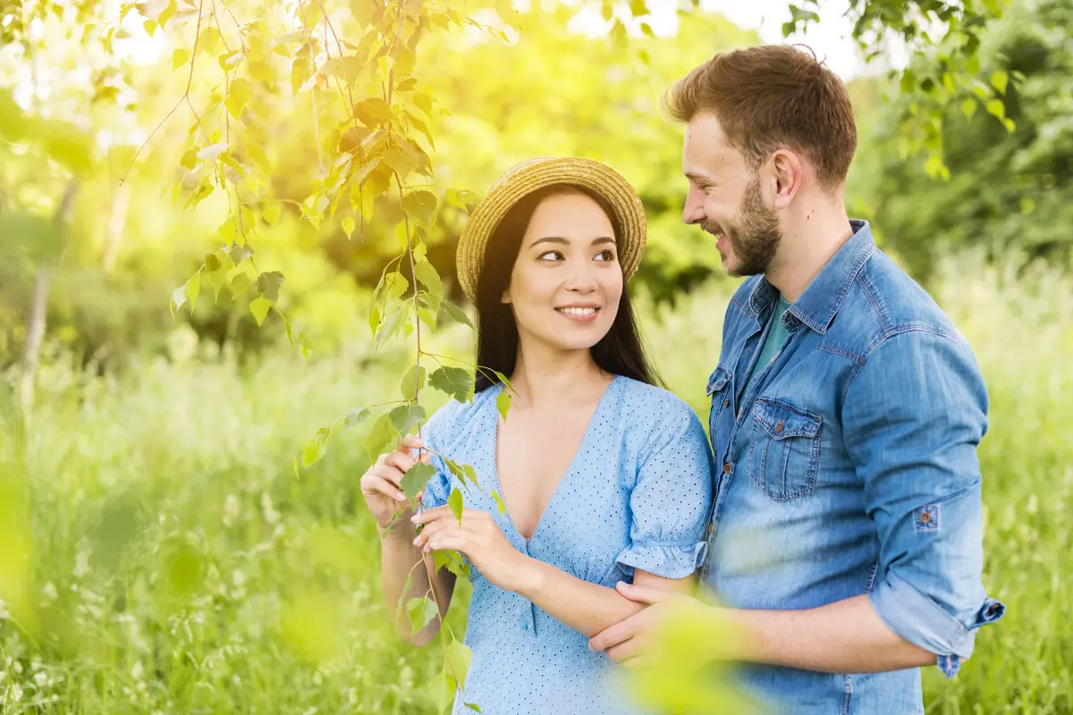 Young cheerful couple smiling at each other with love in nature