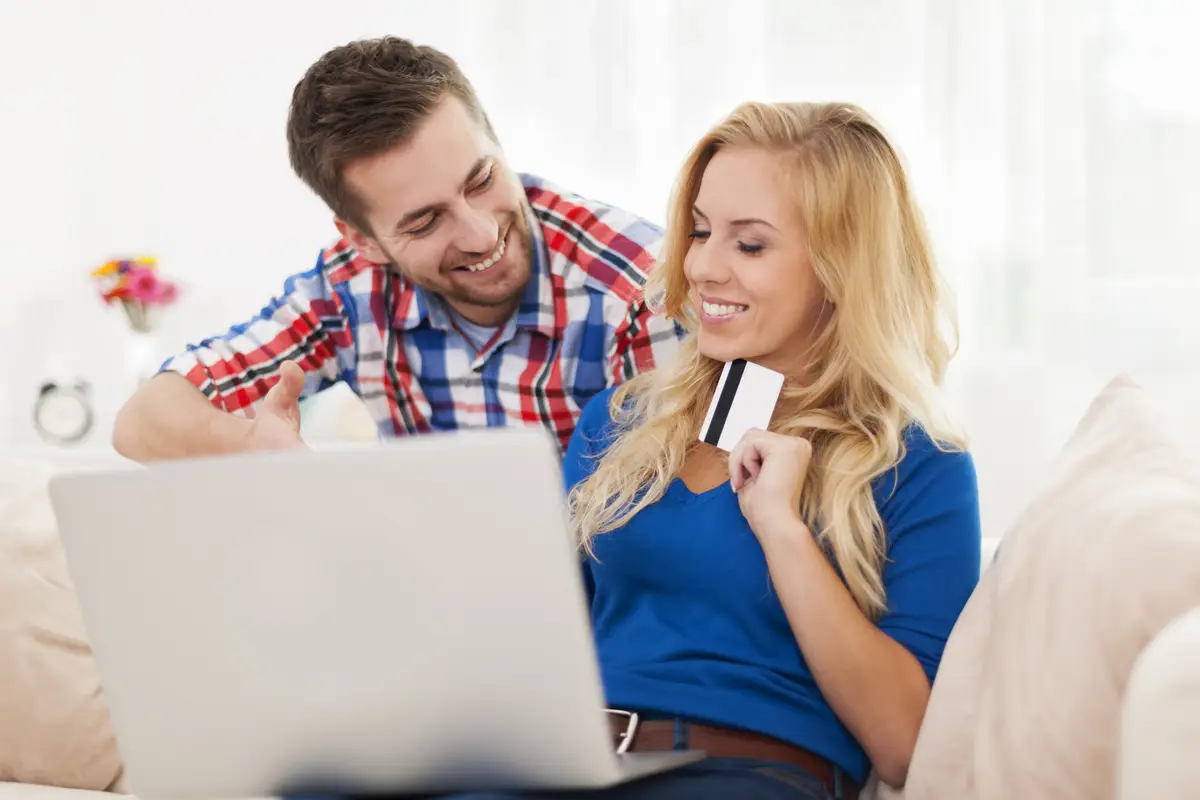 Portrait of couple with laptop and credit card in living room