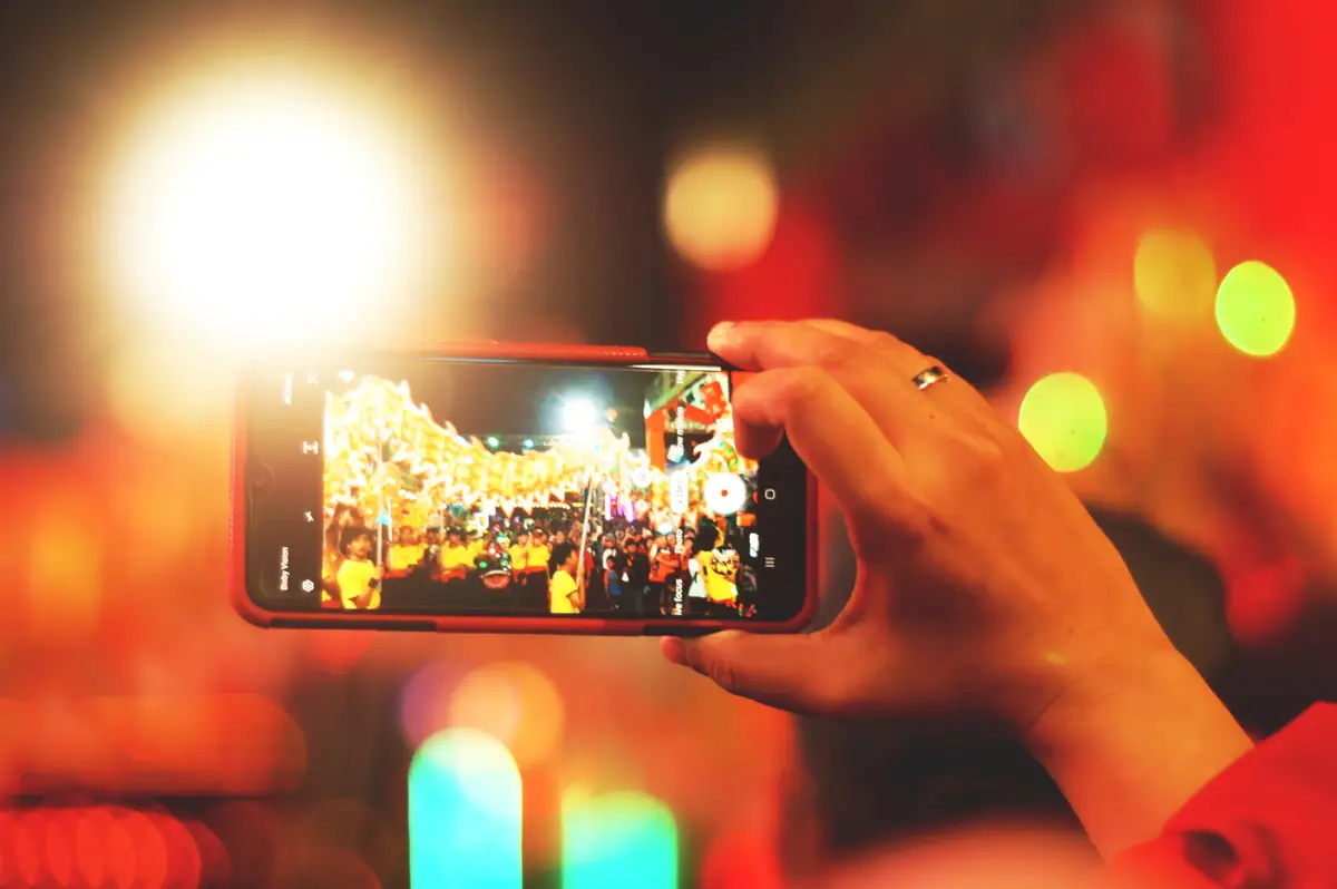 Cropped hand of person photographing at night with smart phone