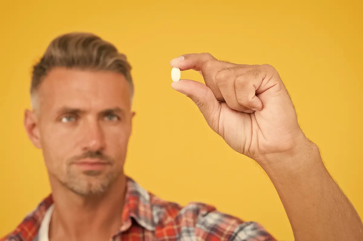 Vitamin pill in hand Side effects Medicines concept Hemp derived CBD Food additives vitamins for male health Vitamin complex Handsome mature man presenting product Drugs pills close up