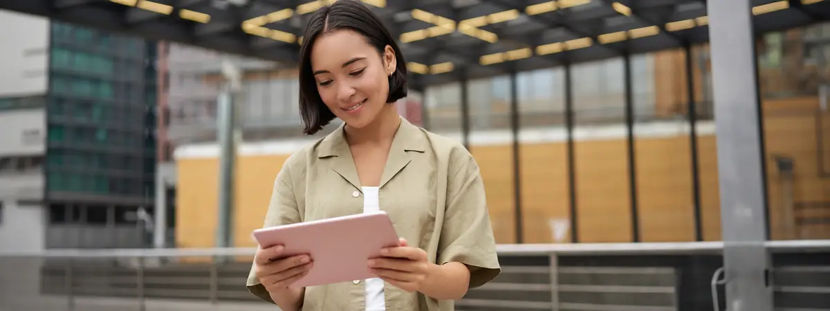 Portrait of beautiful asian girl using tablet reading looking at tablet while standing on street
