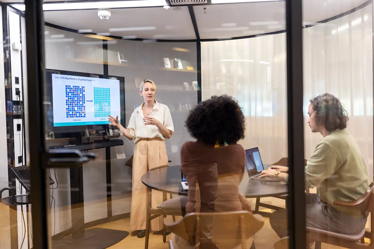 Mature businesswoman giving a presentation to colleagues on a television screen