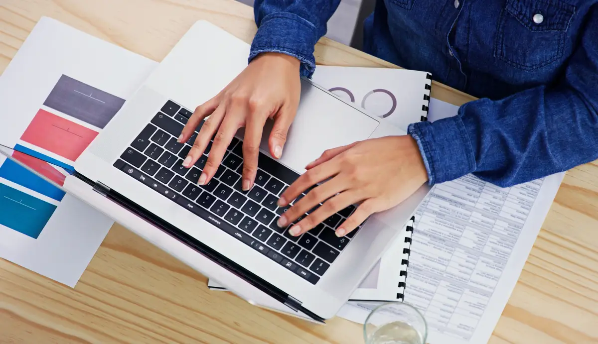 Hands laptop and finance from above with a business woman typing on a keyboard in her accounting office Computer documents and financial budget with an employee planning an investment strategy