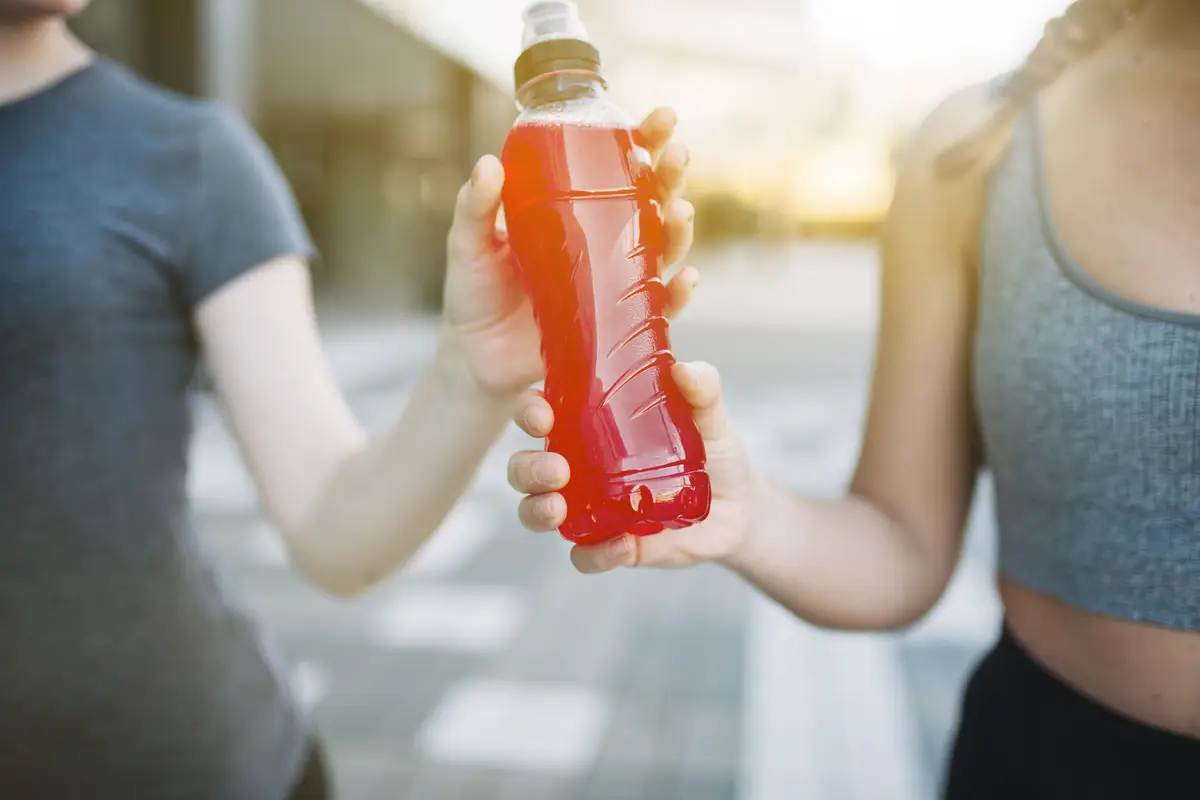 Crop women with red drink in bottle