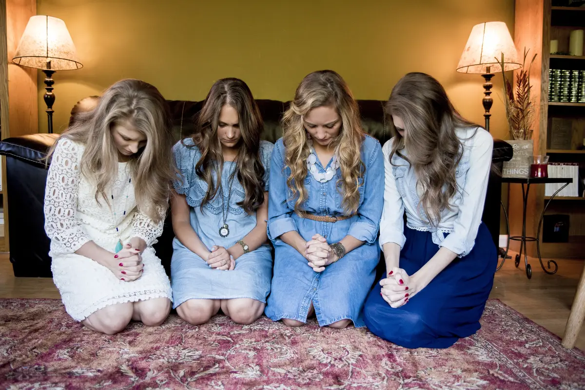 Young girls next to each other looking down in a room
