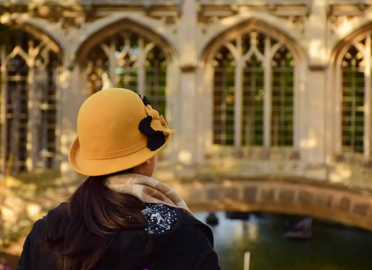 Rear view of woman in hat standing against building