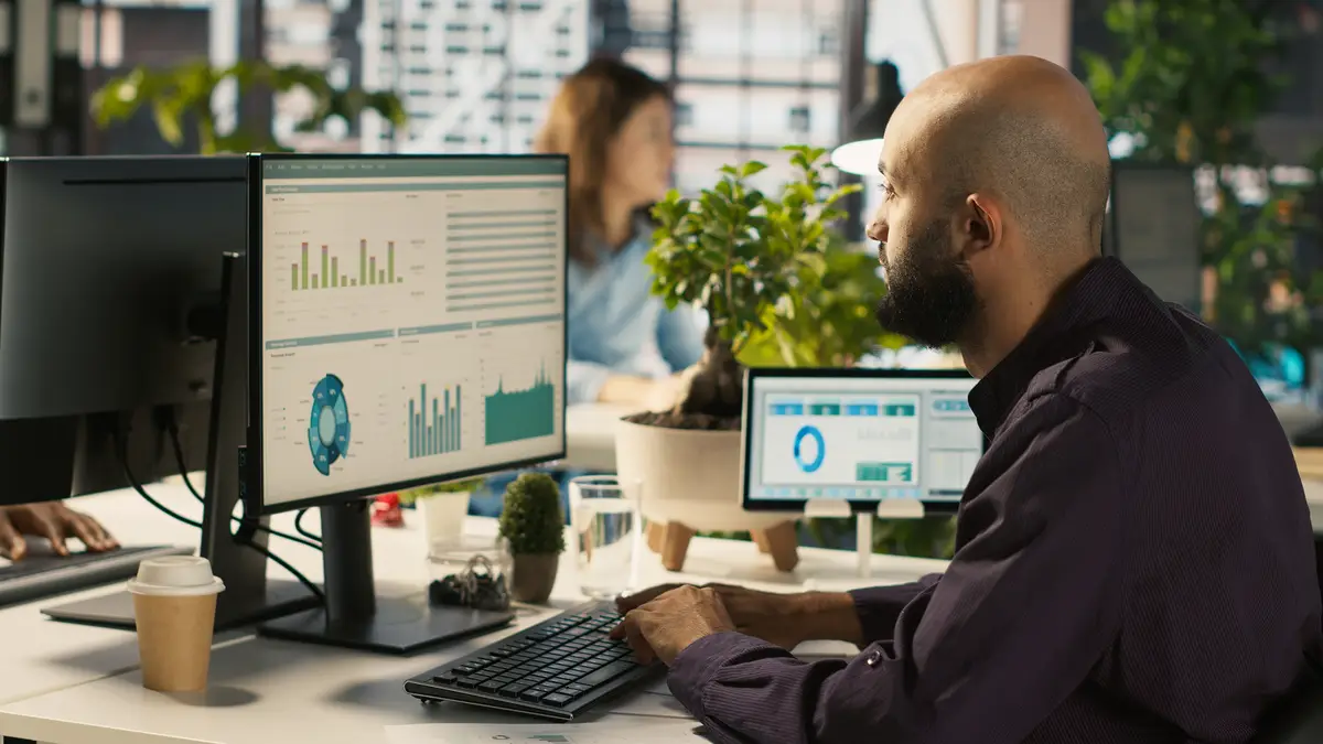Employee editing documents on desktop computer at office desk