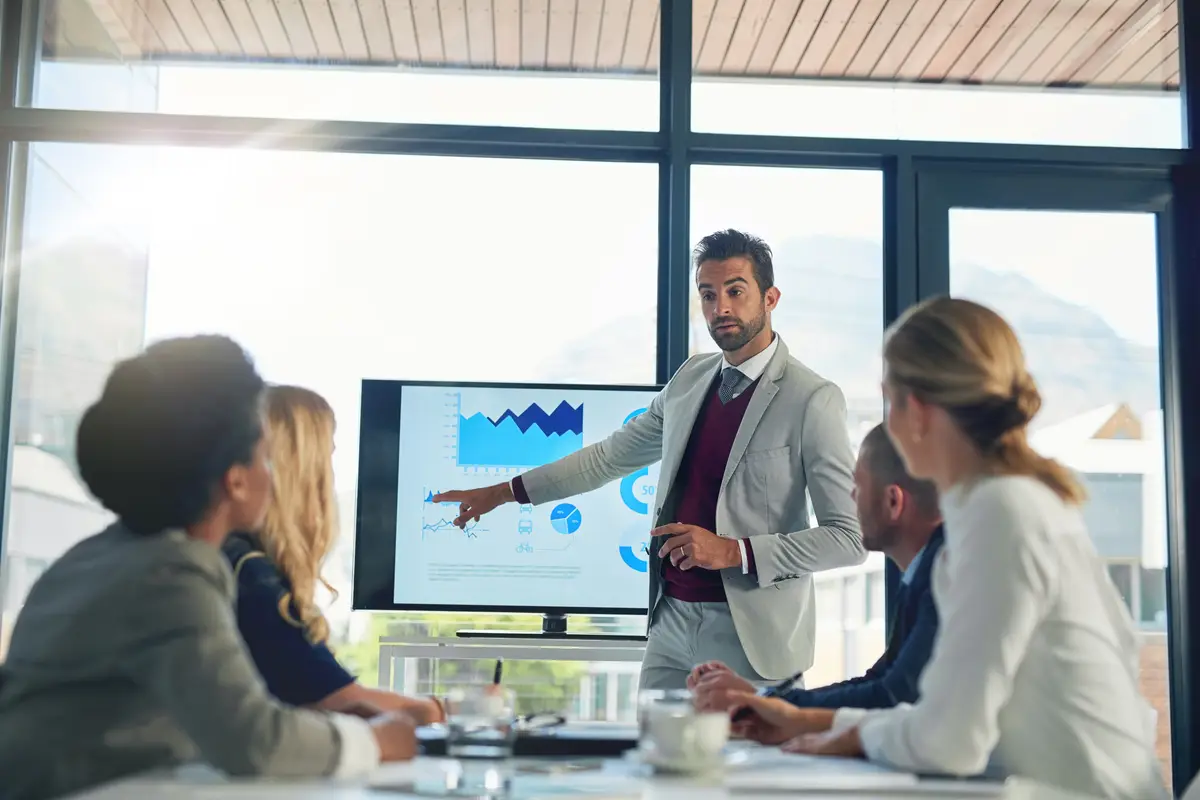 Charts boardroom and stats for man meeting and pointing of stock market for growth and sales Group employee and people in presentation for finance increase and investment of auditor in business
