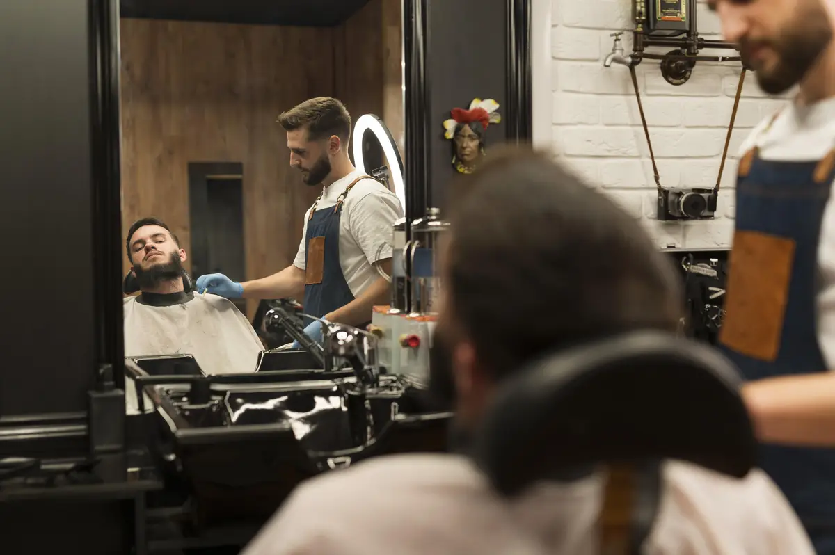 Young man getting his beard styled at the barber