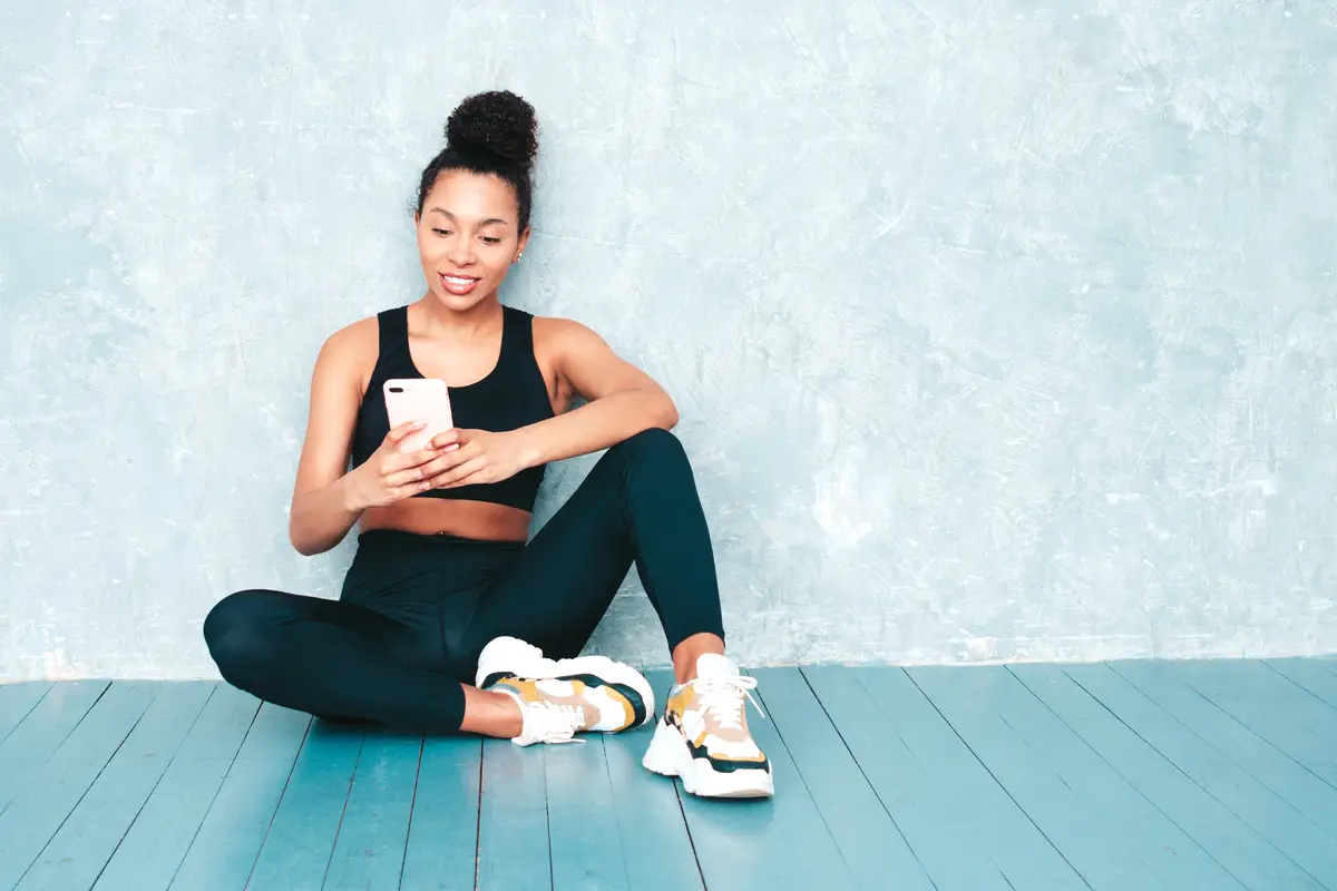 Fitness smiling woman in sports clothing with afro curls hairstyle